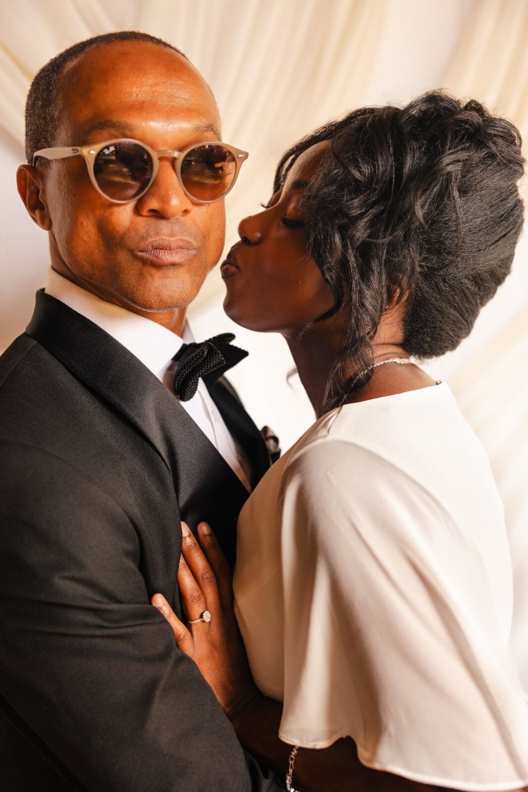 Black bride kissing groom on cheek during Black Romance London editorial at Prince of Peckham