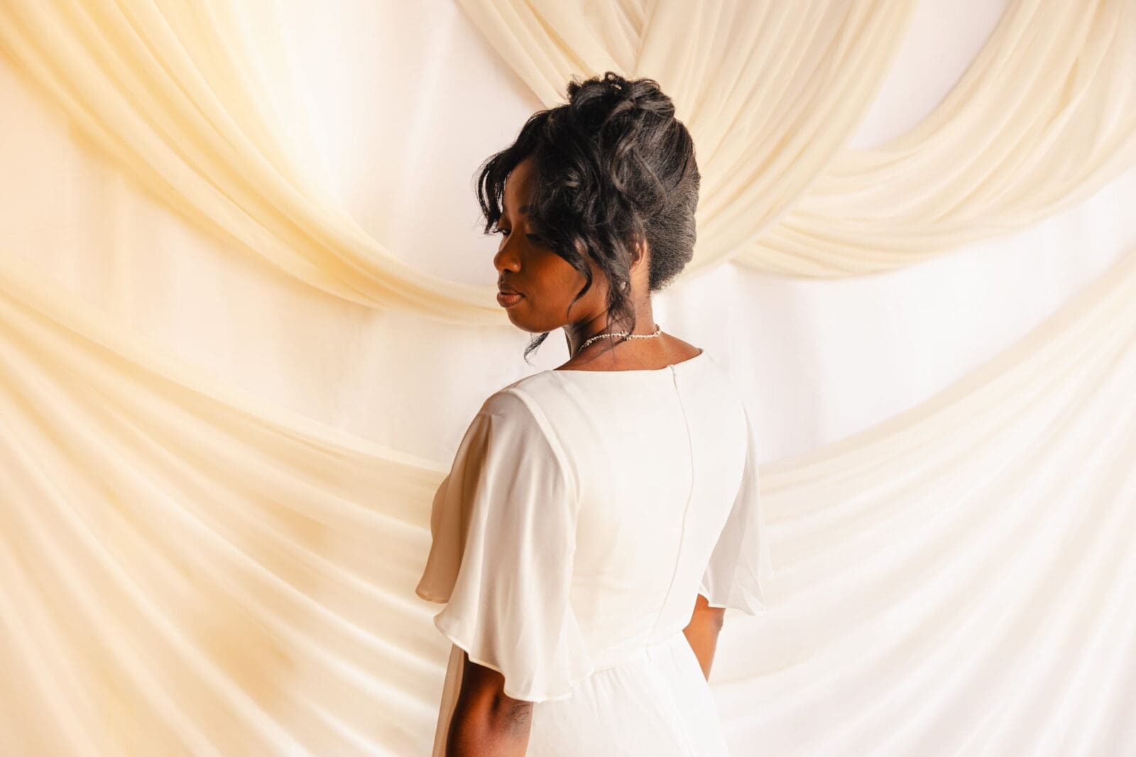 Black bride in ivory chiffon gown photographed from behind during Black Romance London editorial at Prince of Peckham
