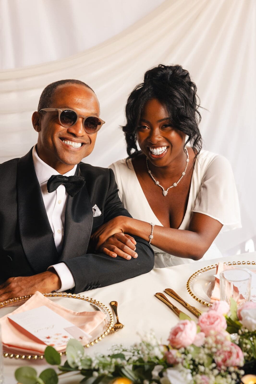 Black couple laughing together at decorated wedding table during Black Romance London editorial at Prince of Peckham