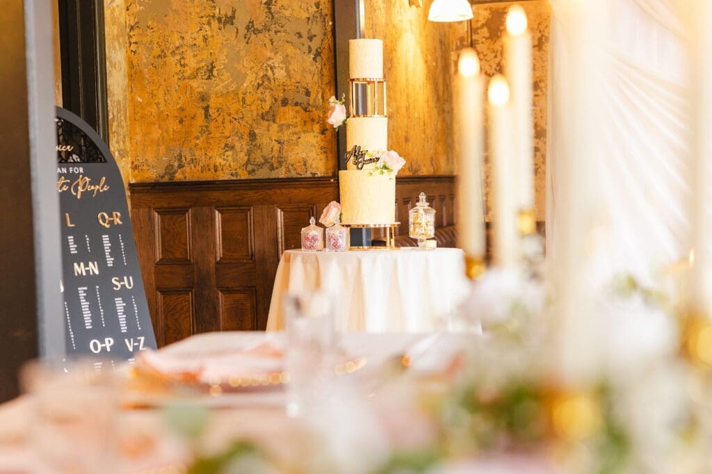 Wedding cake and seating plan styled against warm textured walls during Black Romance London editorial at Prince of Peckham