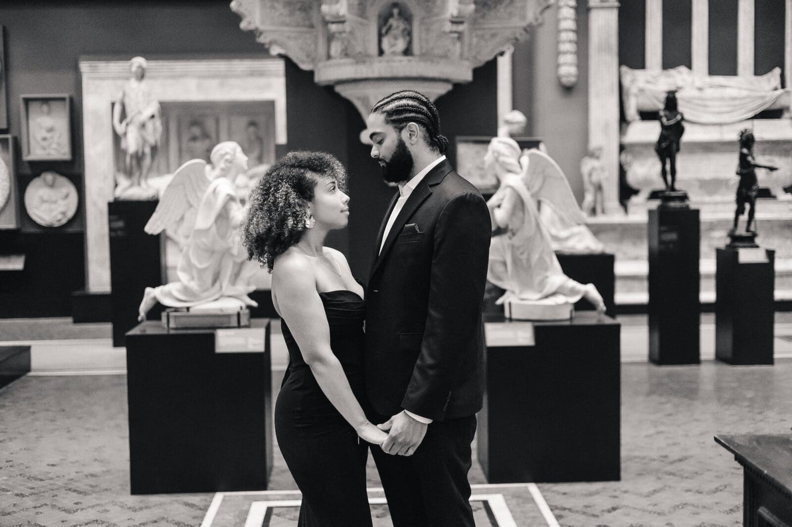 Couple standing among classical sculptures during Victoria and Albert Museum engagement session in London