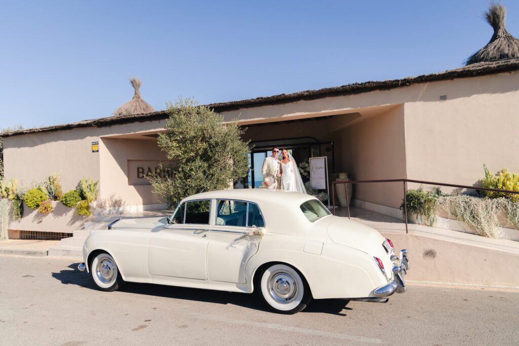 Anna and Michael standing outside their reception venue with a Rolls-Royce parked beside them