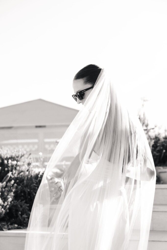 Anna wearing sunglasses and partially obscured by her flowing veil, photographed in black and white