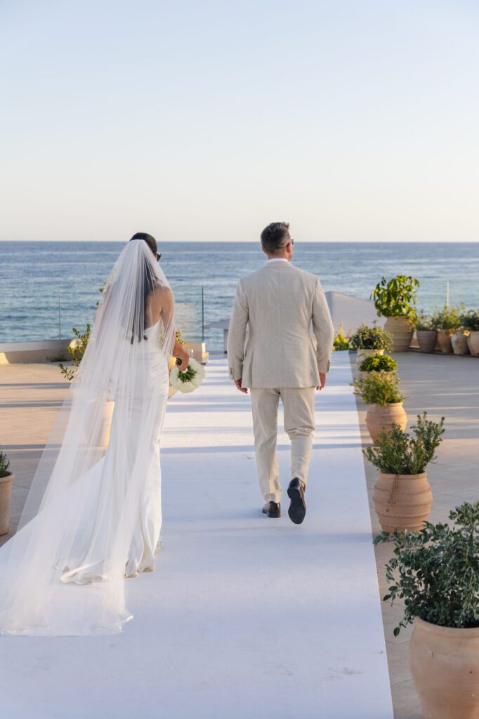 Anna and Michael walking hand in hand towards the ocean views with their backs to the camera