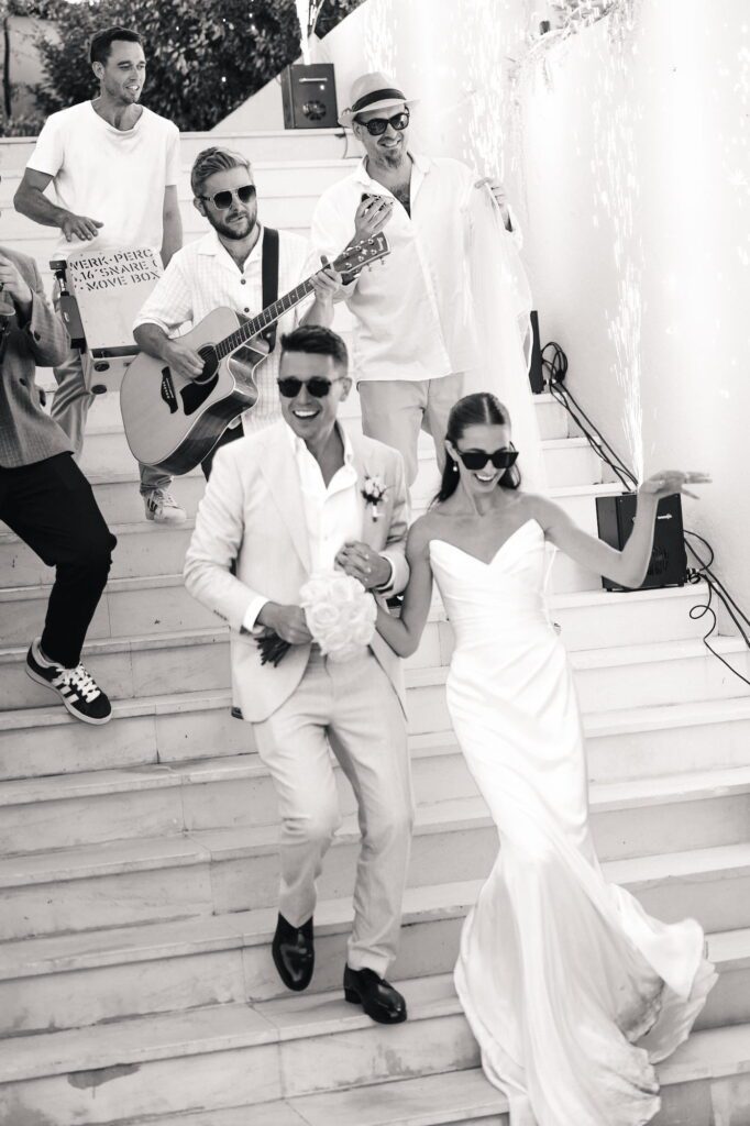 Anna and Michael walking downstairs towards their wedding guests with the live band playing behind them