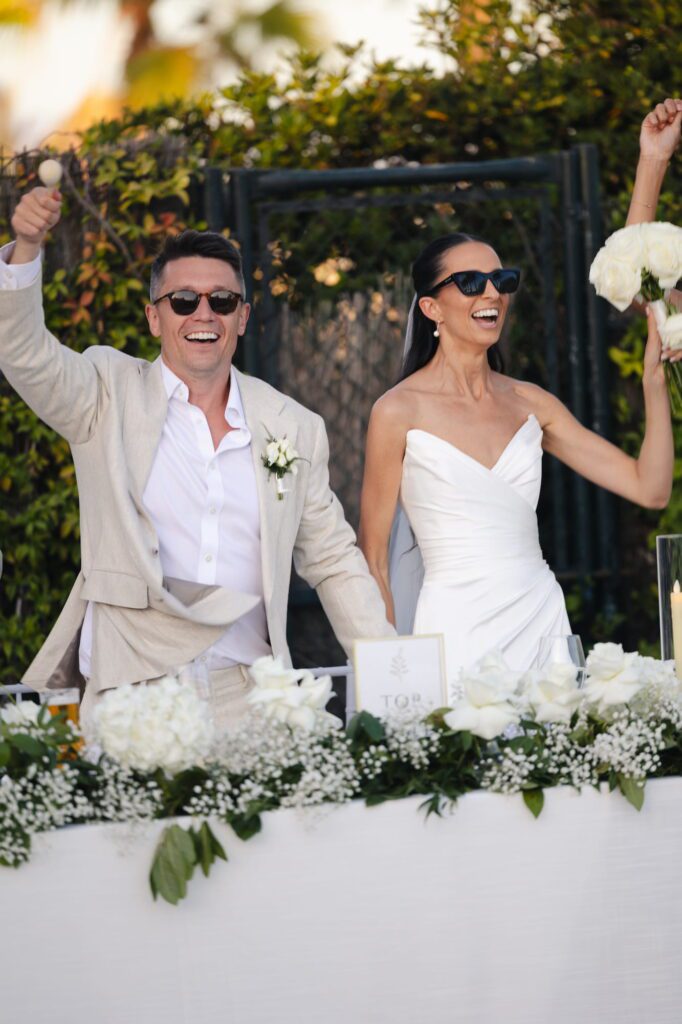 Anna and Michael standing beside their sweetheart table and smiling